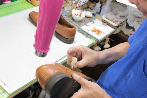革靴へ手作業で色を重ね、乾かしながら調整する工程。形や縫い目に沿って仕上げます。