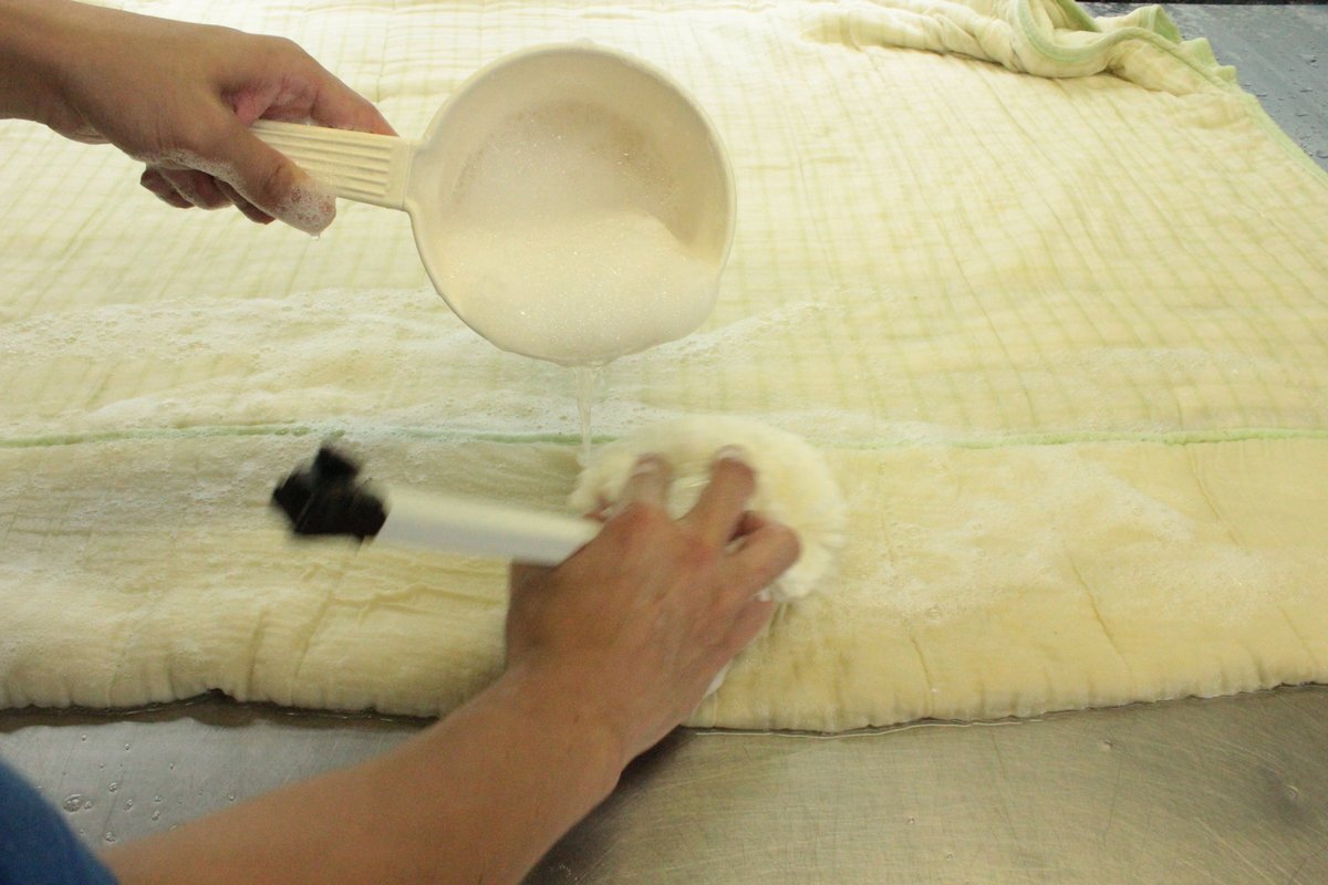 布団の表面へ石けんの泡で手作業を施す工程です。