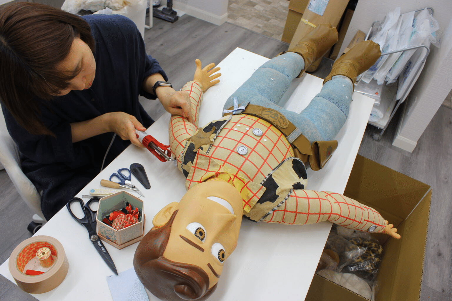 ぬいぐるみを作業台に支え、一か所ずつ手作業で修復しています。