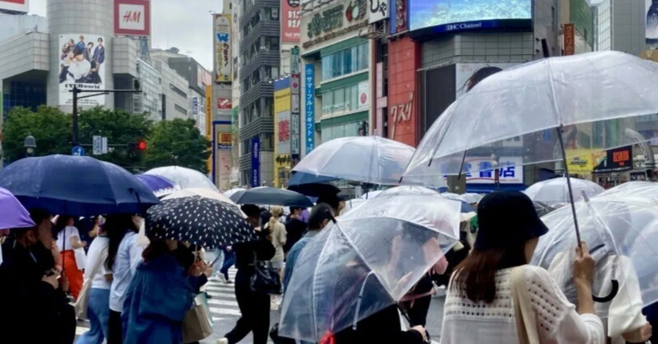 雨の日に傘を差して街を歩く人々。店舗への移動を考えるイメージ