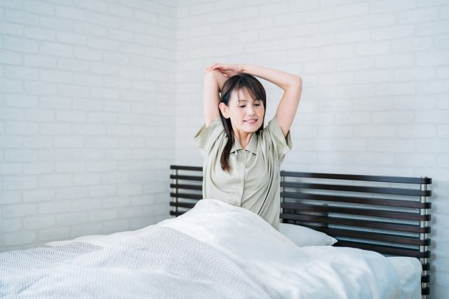 朝、寝具の上で伸びをするイメージ。個別の効果を表す写真ではありません。
