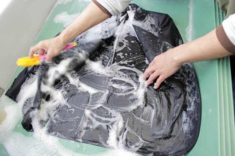 ジャケットを作業台に広げ、泡で部分洗いする工程。