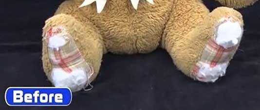 チェック柄の足裏の生地が擦り切れたクマの修理前。