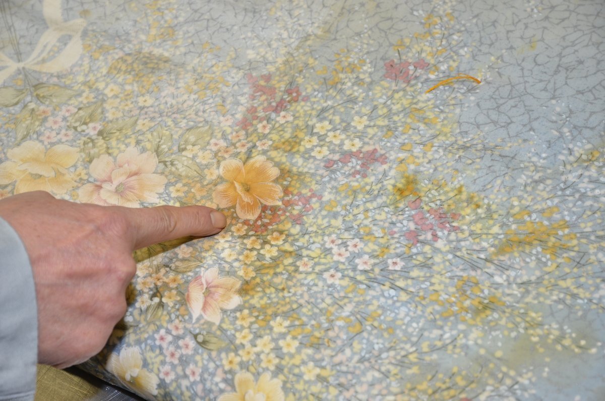 花柄の布団の生地や汚れを指で確認する検品作業。